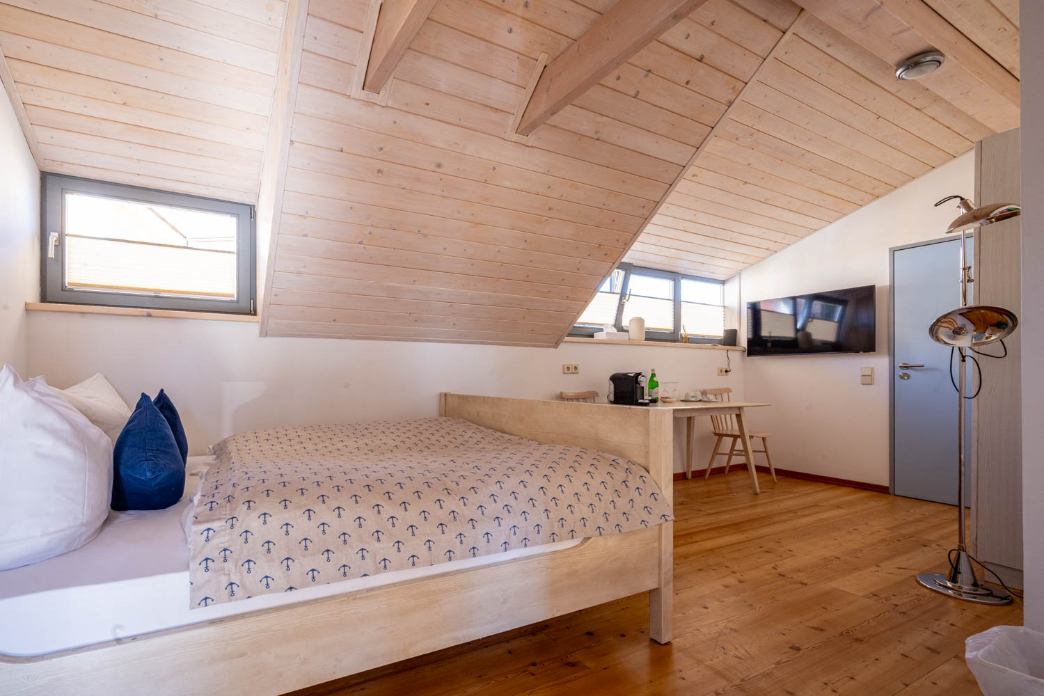 [Doppelzimmer »Koje 1« 402] Helles Doppelzimmer im Neuen Fährgut mit gemütlichem Doppelbett, Blick auf die Dorfstraße zur Elbe und Zugang zur gemeinsamen Terrasse mit Zimmer 403.