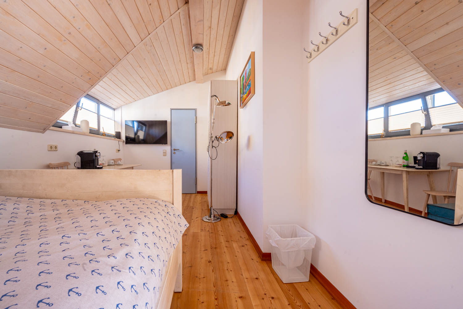 [Doppelzimmer »Koje 1« 402] Helles Doppelzimmer im Neuen Fährgut mit gemütlichem Doppelbett, Blick auf die Dorfstraße zur Elbe und Zugang zur gemeinsamen Terrasse mit Zimmer 403.