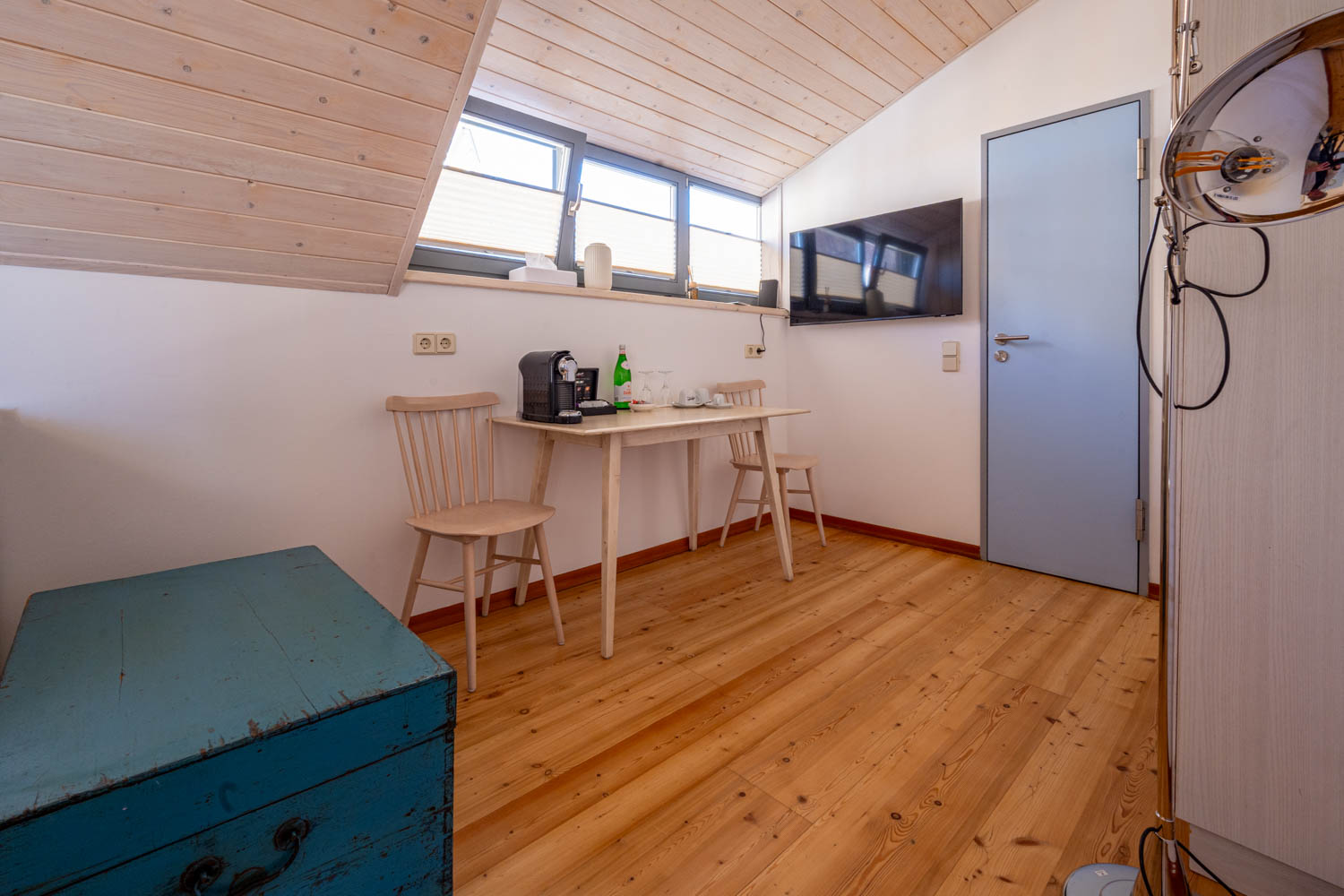 [Doppelzimmer »Koje 1« 402] Helles Doppelzimmer im Neuen Fährgut mit gemütlichem Doppelbett, Blick auf die Dorfstraße zur Elbe und Zugang zur gemeinsamen Terrasse mit Zimmer 403.