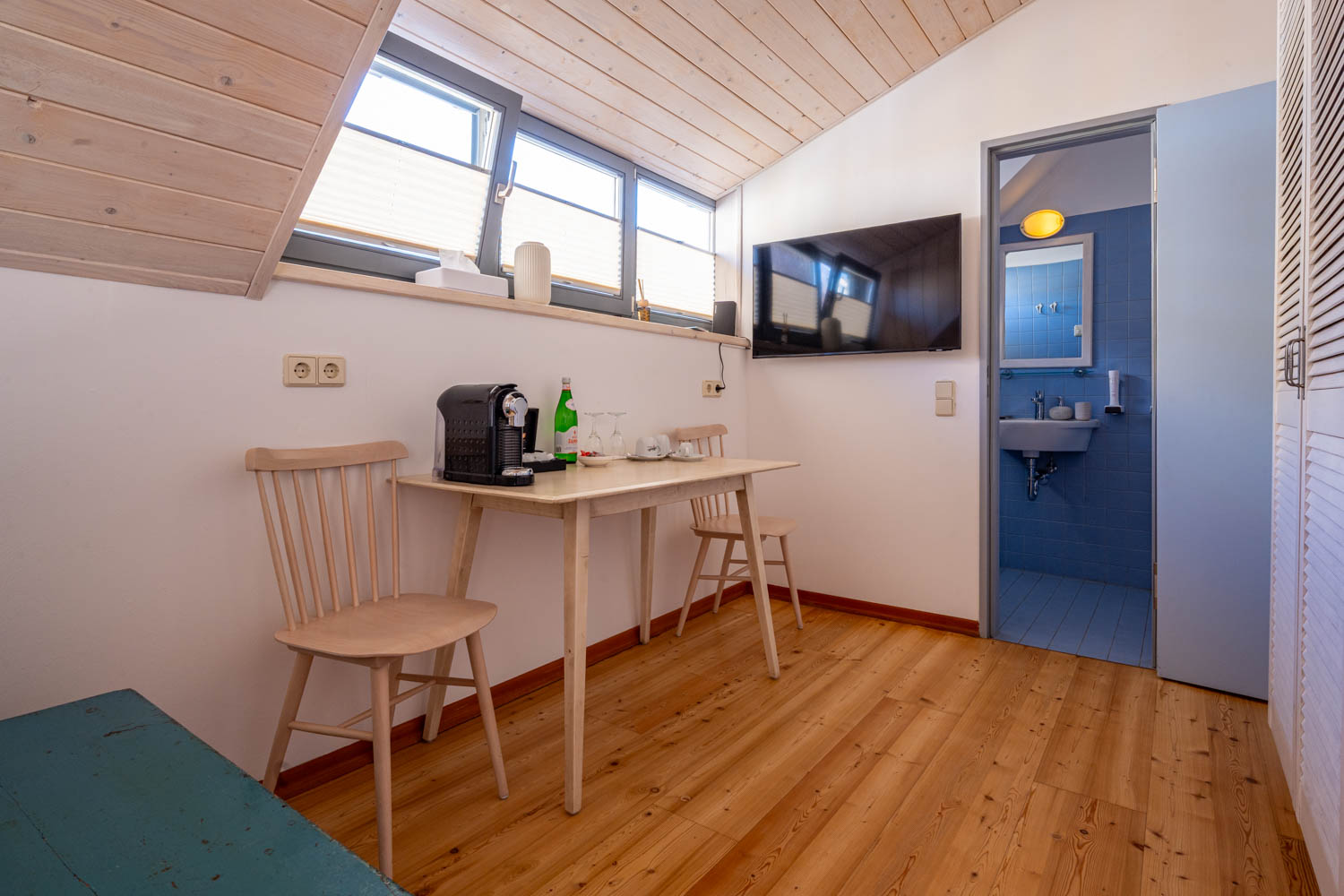 [Doppelzimmer »Koje 1« 402] Helles Doppelzimmer im Neuen Fährgut mit gemütlichem Doppelbett, Blick auf die Dorfstraße zur Elbe und Zugang zur gemeinsamen Terrasse mit Zimmer 403.