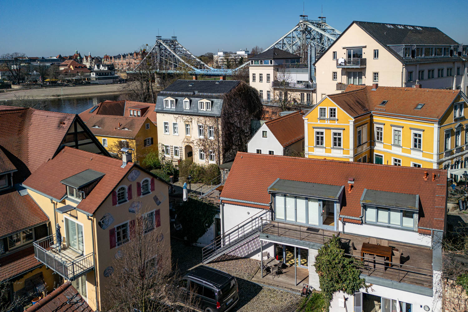 [Doppelzimmer »Koje 1« 402] Helles Doppelzimmer im Neuen Fährgut mit gemütlichem Doppelbett, Blick auf die Dorfstraße zur Elbe und Zugang zur gemeinsamen Terrasse mit Zimmer 403.
