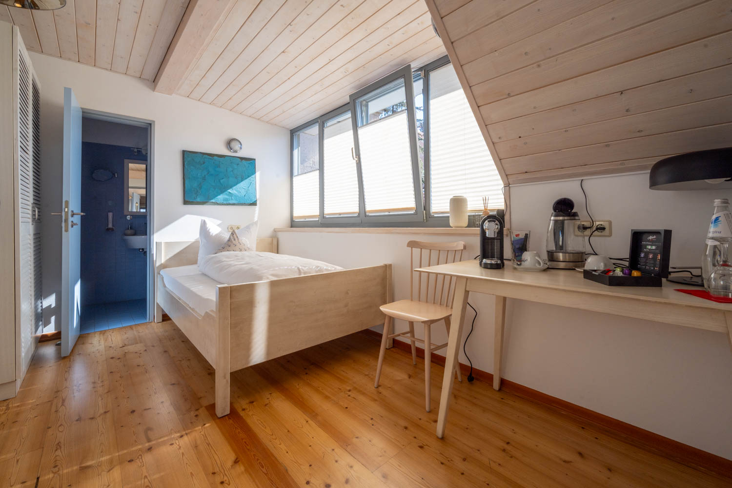 [Einzelzimmer »Koje 2« 403] Helles Einzelzimmer im Neuen Fährgut mit bequemem Bett, Blick auf die Dorfstraße zur Elbe und Zugang zur gemeinsamen Terrasse mit Koje 1.