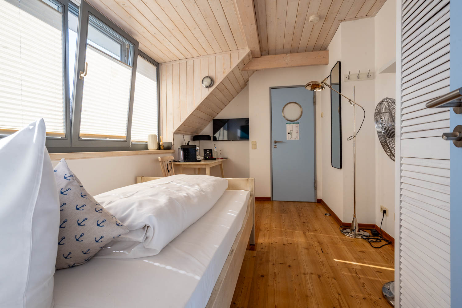 [Einzelzimmer »Koje 2« 403] Helles Einzelzimmer im Neuen Fährgut mit bequemem Bett, Blick auf die Dorfstraße zur Elbe und Zugang zur gemeinsamen Terrasse mit Koje 1.