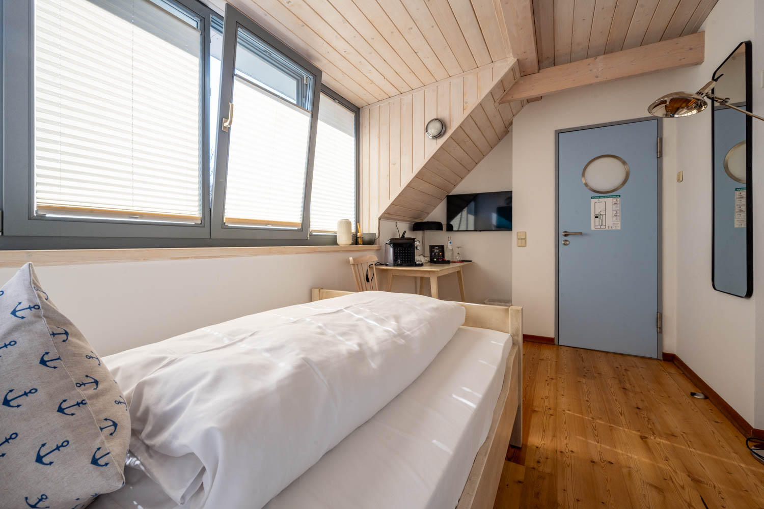[Einzelzimmer »Koje 2« 403] Helles Einzelzimmer im Neuen Fährgut mit bequemem Bett, Blick auf die Dorfstraße zur Elbe und Zugang zur gemeinsamen Terrasse mit Koje 1.