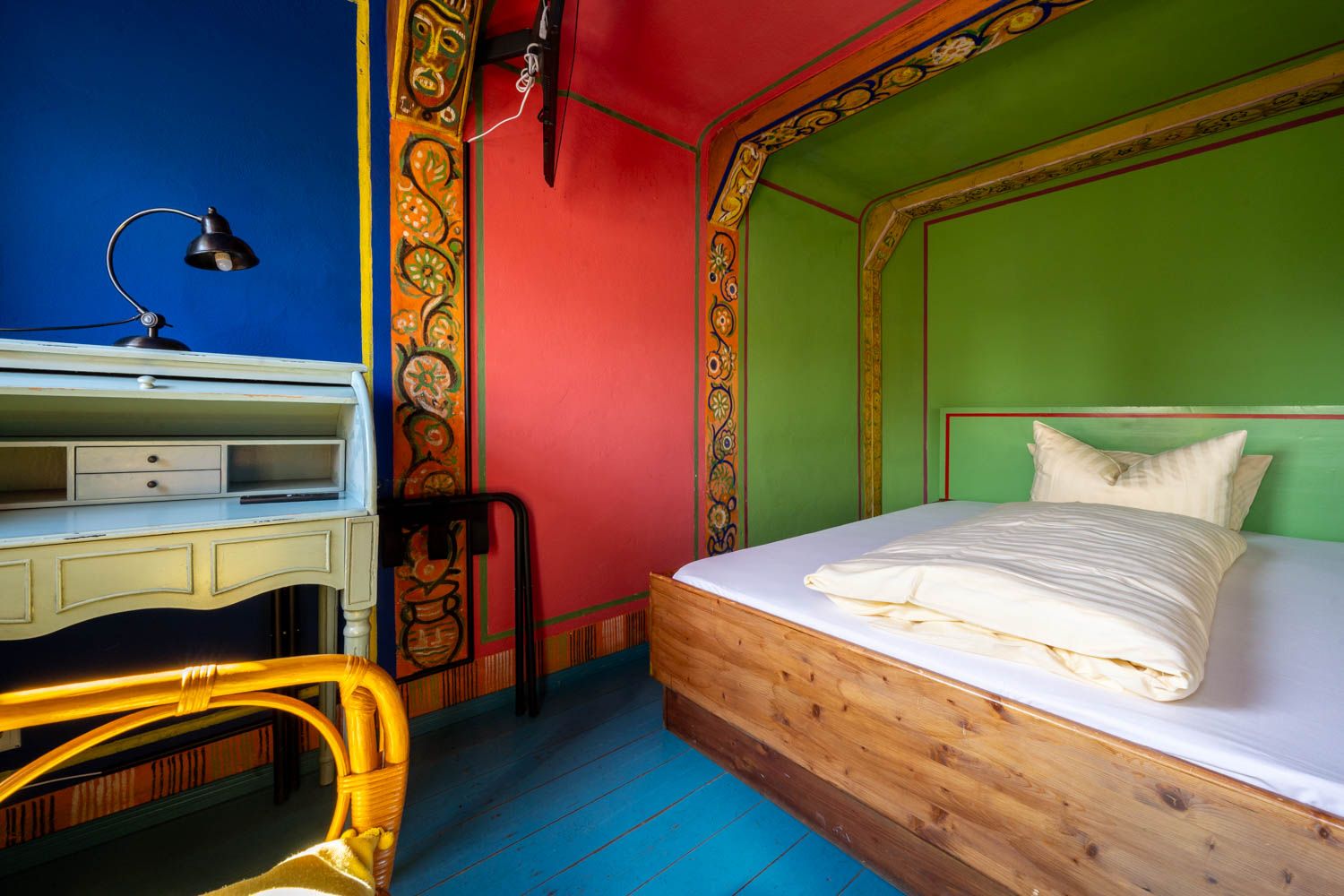 [Einzelzimmer 203 Böckstiegel] Kompaktes Einzelzimmer mit künstlerisch gestalteten Böckstiegel-Wänden, bequemen Bett und liebevollen Details im historischen Alten Fährgut.