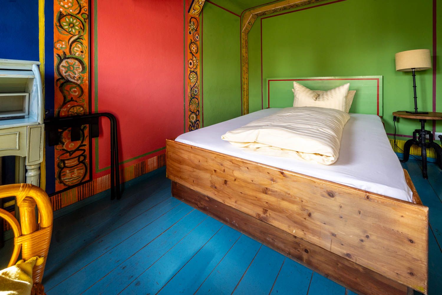 [Einzelzimmer 203 Böckstiegel] Kompaktes Einzelzimmer mit künstlerisch gestalteten Böckstiegel-Wänden, bequemen Bett und liebevollen Details im historischen Alten Fährgut.